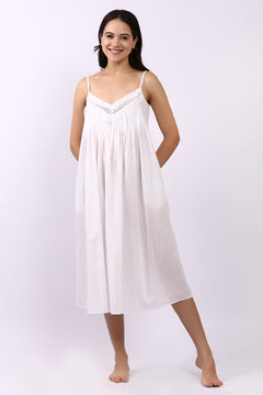 Woman wearing Lotus Susie spaghetti strap white cotton nightdress with lace-trim neckline and pintuck bodice.