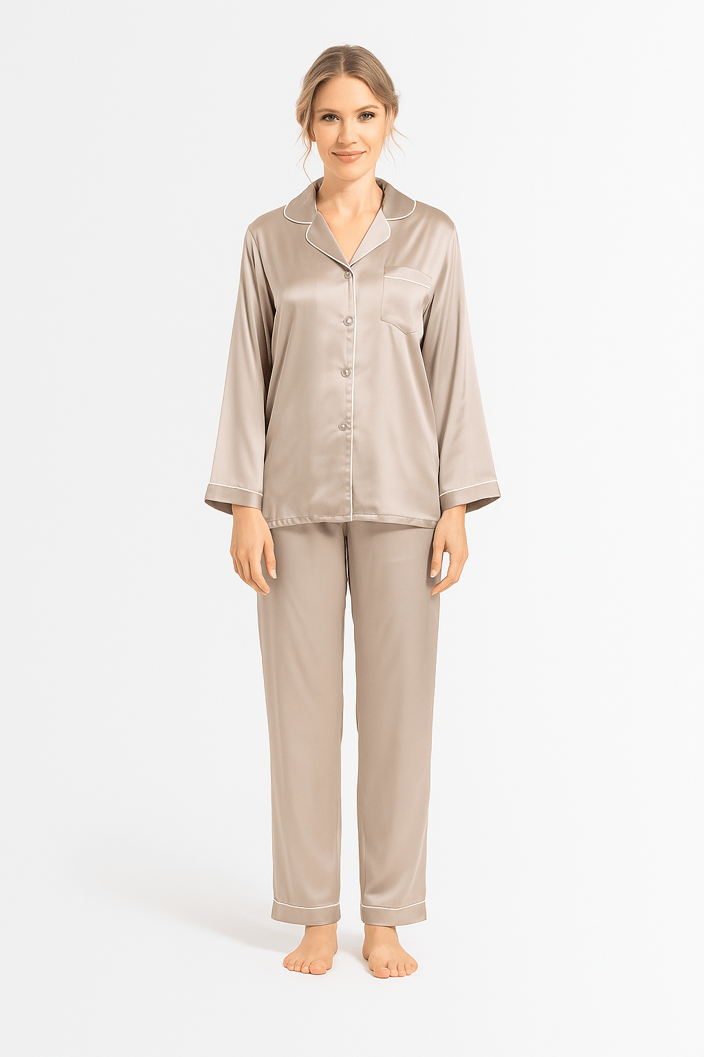 Woman wearing a beige silk pajama set with ivory piping details on a white background