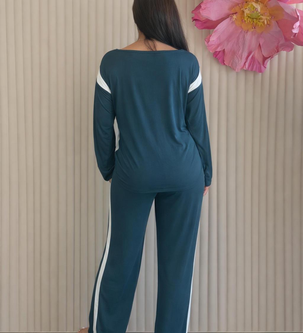 Woman wearing a teal outfit with white stripes standing in front of a floral arrangement.