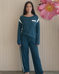 Woman wearing a teal tracksuit standing in front of a beige wall with decorative flowers.