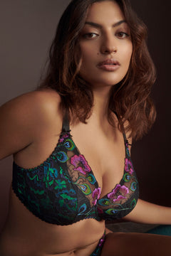 Confident woman in Prima Donna San Angel Half Padded Plunge Bra Peacock Feather, peacock blues and greens glowing against black, styled by The Foundation.