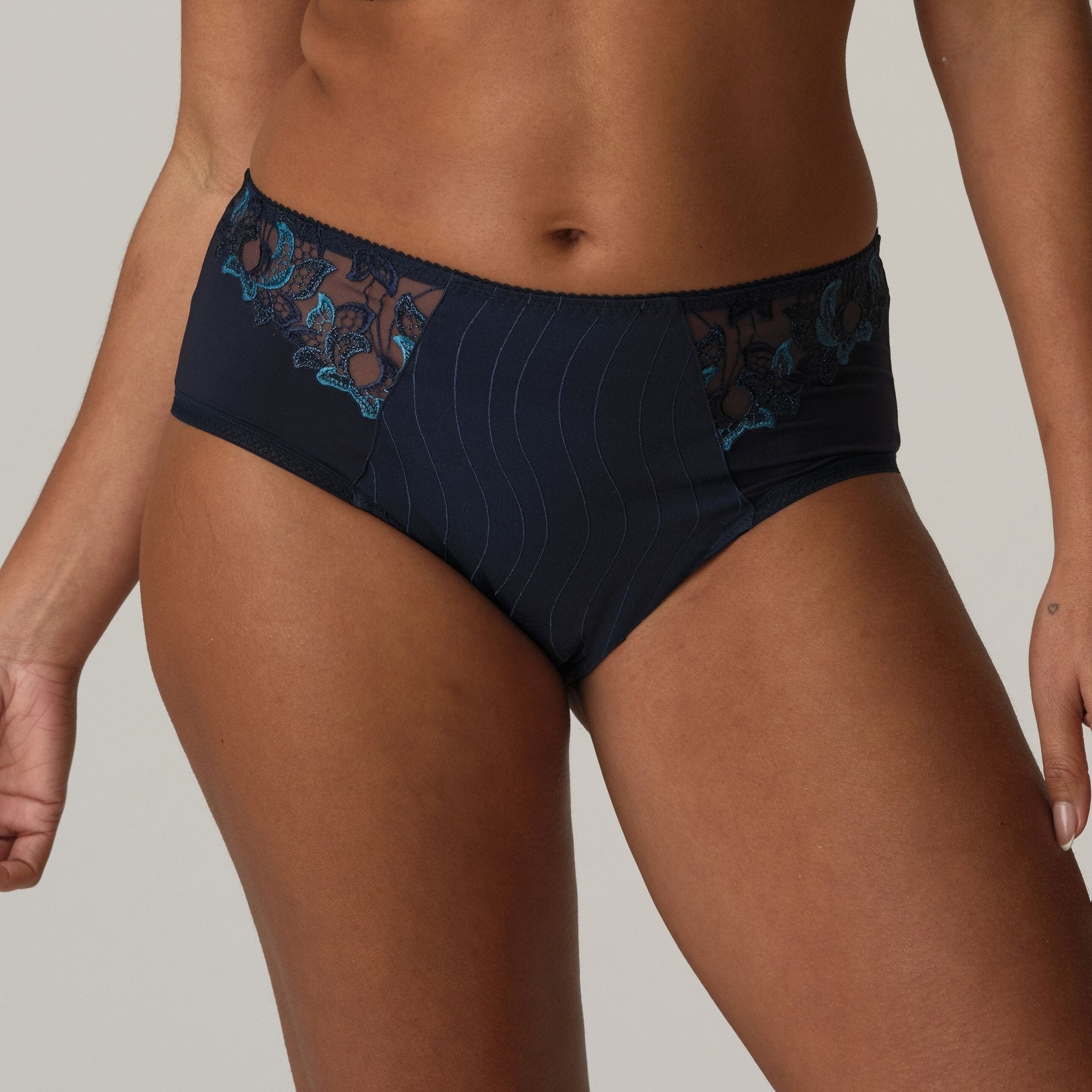 Model wearing PrimaDonna Deauville Full Briefs Velvet Blue, showcasing elegant high waist fit and blue embroidery detail from The Foundation.
