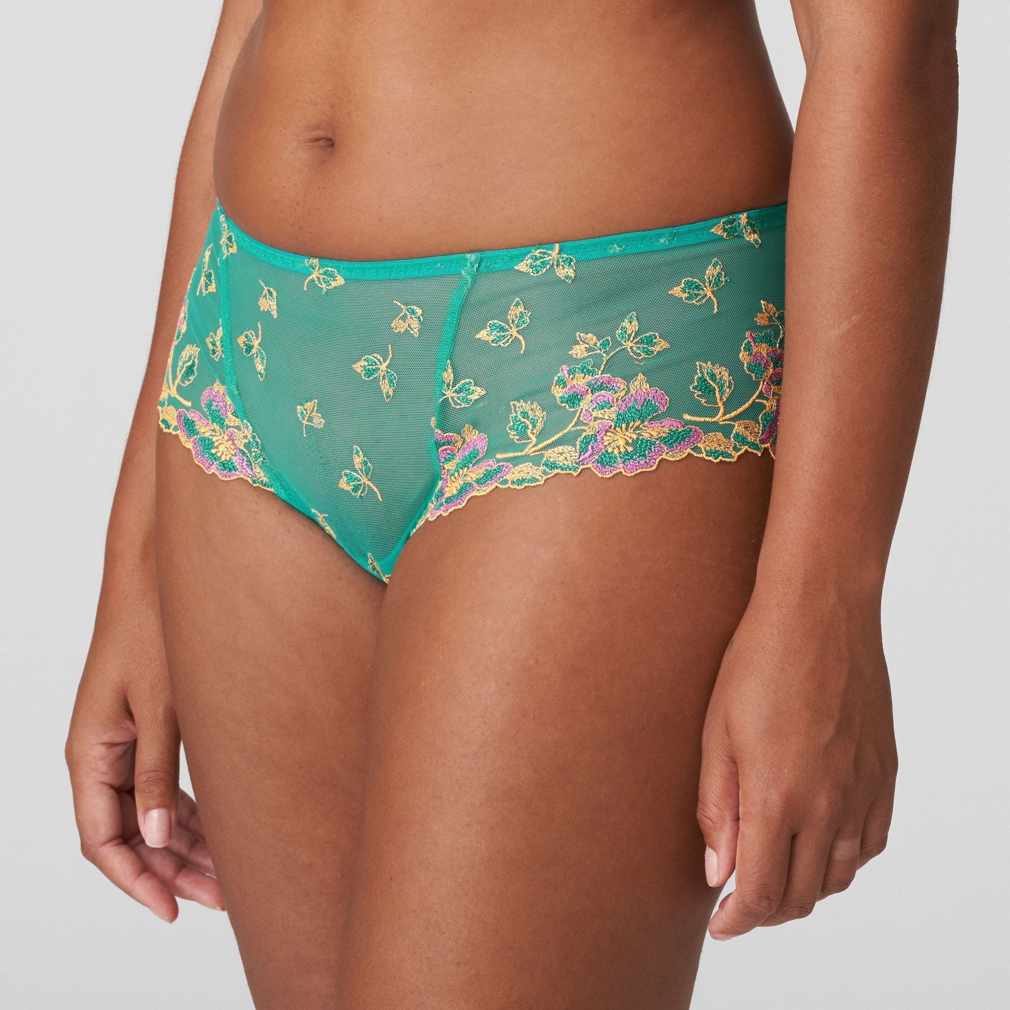 Model wearing Lenca Luxury Thong Sunny Teal from The Foundation, focusing on the low-rise cut and elegant embroidered waistband