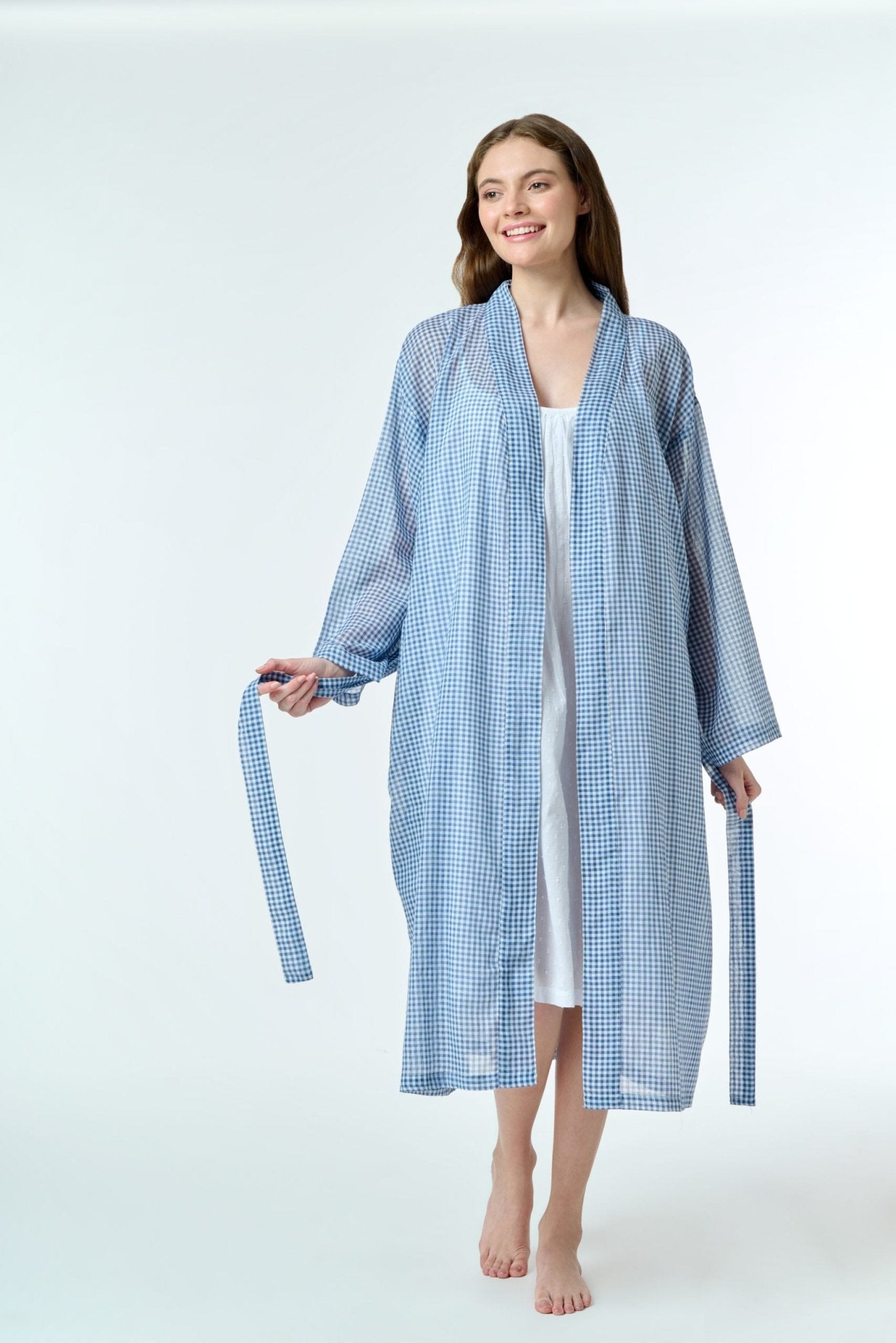 Model wearing Hand Loomed Cotton Robe in navy gingham, featuring lightweight cotton voile and waist tie for airy summer layering.