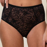 Close up of Model wearing Triumph Amourette Charm Maxi 02 Brief in black, showing floral lace detail and wide sides.