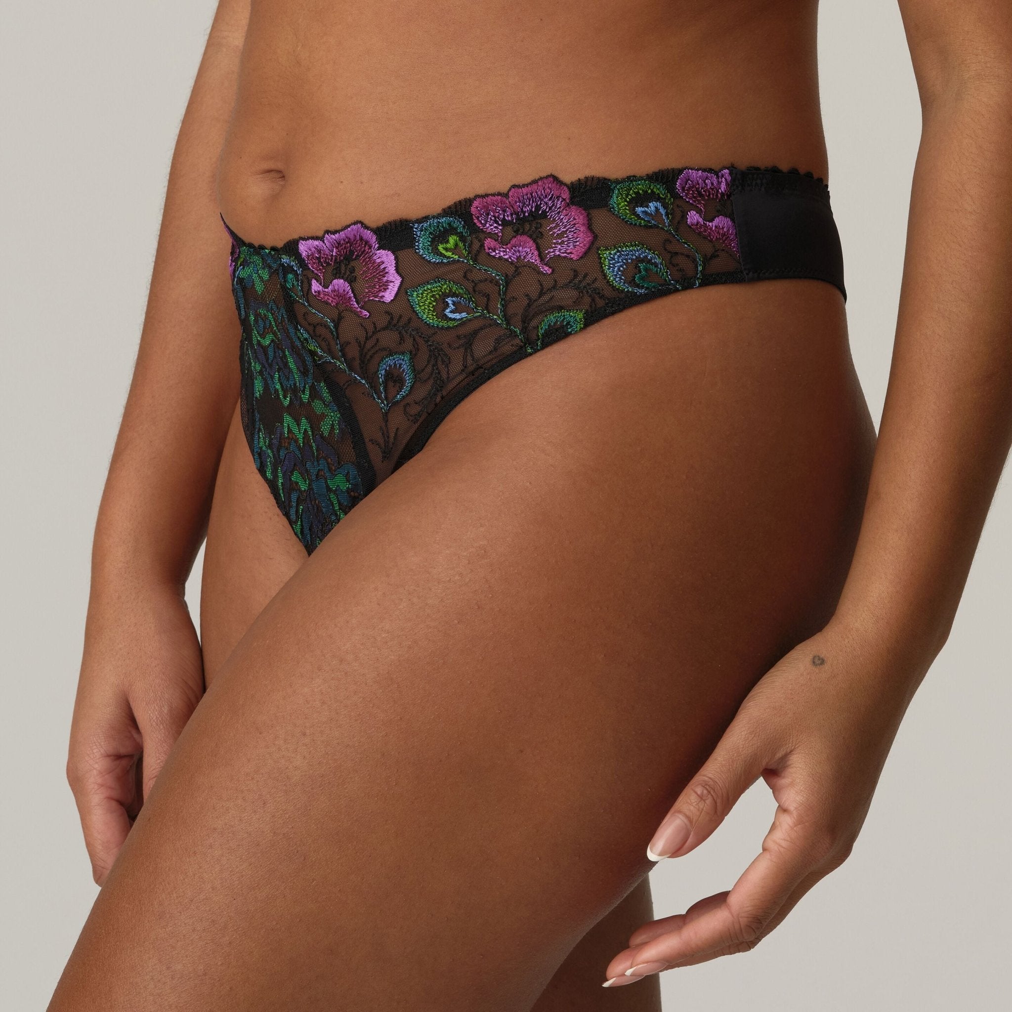 Model wearing Prima Donna San Angel Thong Brief Peacock Feather, close-up on vibrant feather lace and pink highlights from The Foundation.