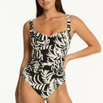 Woman wearing a black and white leaf print swimsuit on a black background