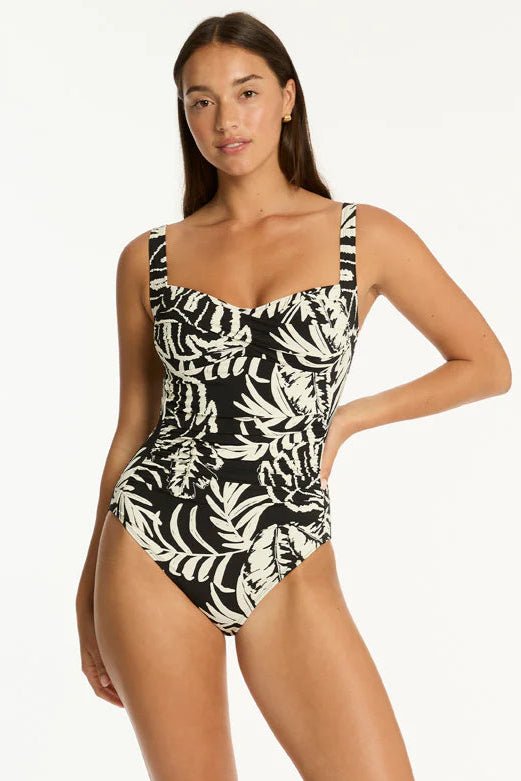 Woman wearing a black and white leaf print swimsuit on a black background
