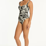 Woman wearing a black and white leaf print swimsuit on a black background