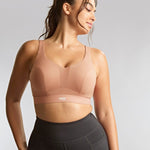 Woman wearing a beige sports bra against a gray background