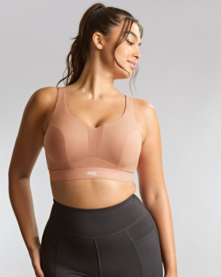 Woman wearing a beige sports bra against a gray background