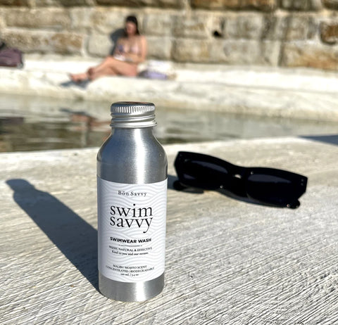 Swim Savvy bottle styled with towel and accessories, evoking a clean and fresh summer feel.