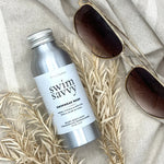 Swim Savvy Laundry Liquid and wash bag on a natural surface with summer essentials.