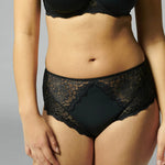 Front view of Simone Pérèle Caresse Culotte Brief in Black, shown on model, featuring high waist design with matte and sheer lace front panel.