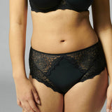 Front view of Simone Pérèle Caresse Culotte Brief in Black, shown on model, featuring high waist design with matte and sheer lace front panel.