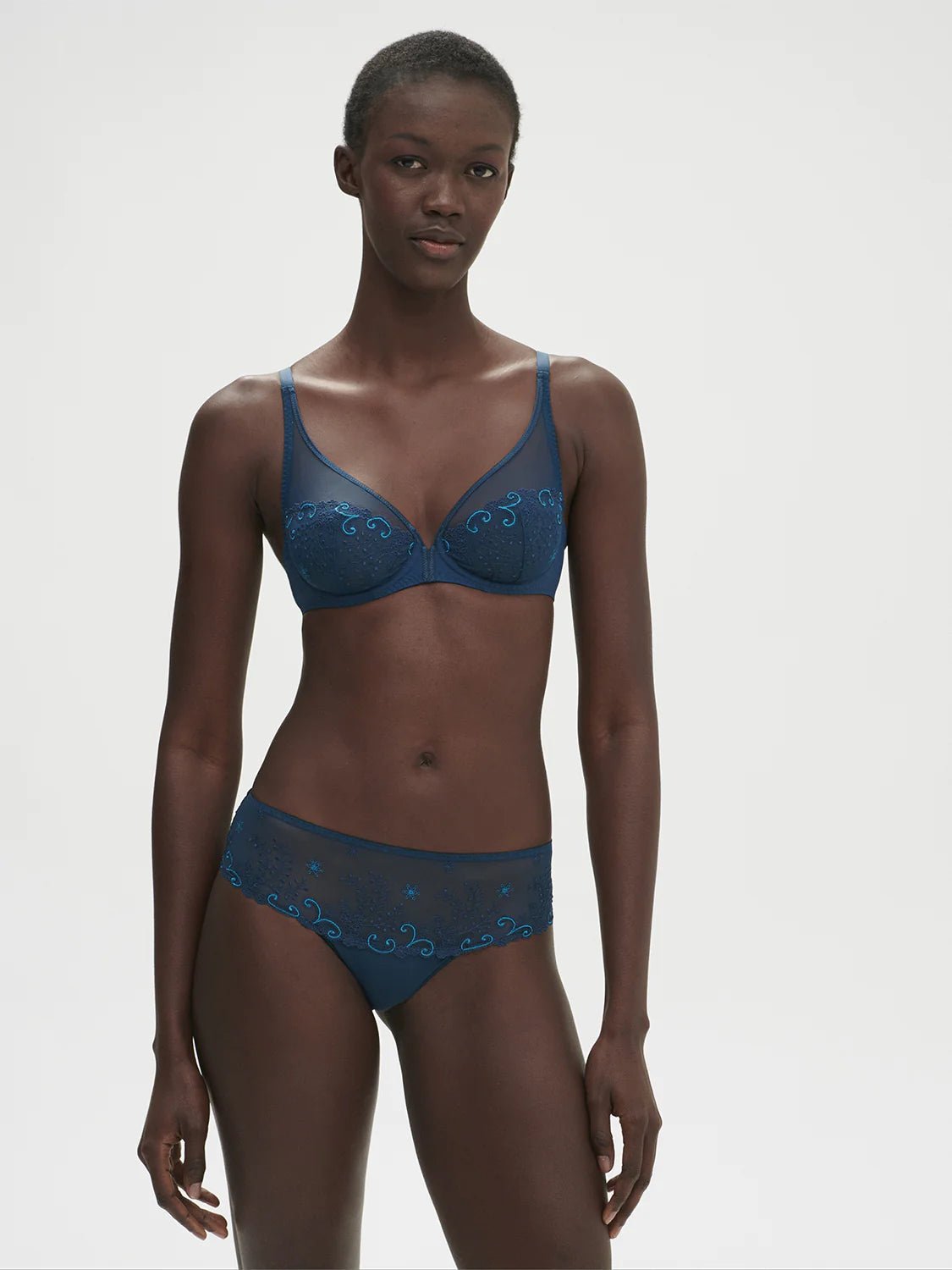 Model wearing the Simone Perele Delice Full Cup Plunge Bra in Prestige Blue featuring sheer embroidered detail and deep plunge fit.