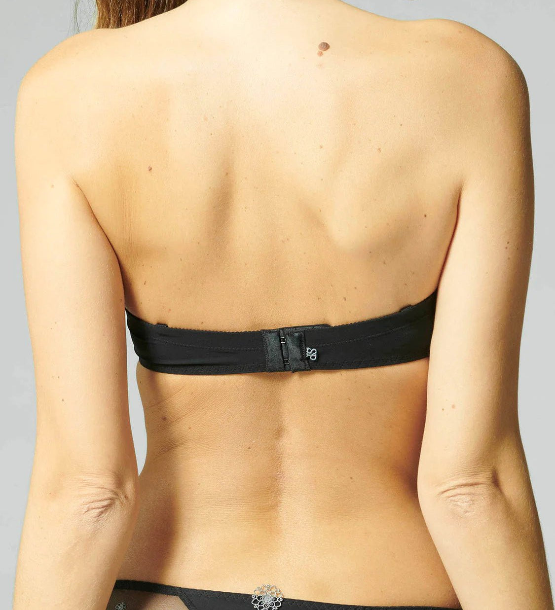 Model wearing Simone Pérèle Delice Strapless Bra in Moonlight from The Foundation, featuring smooth microfibre cups and embroidered tulle detailing. back view