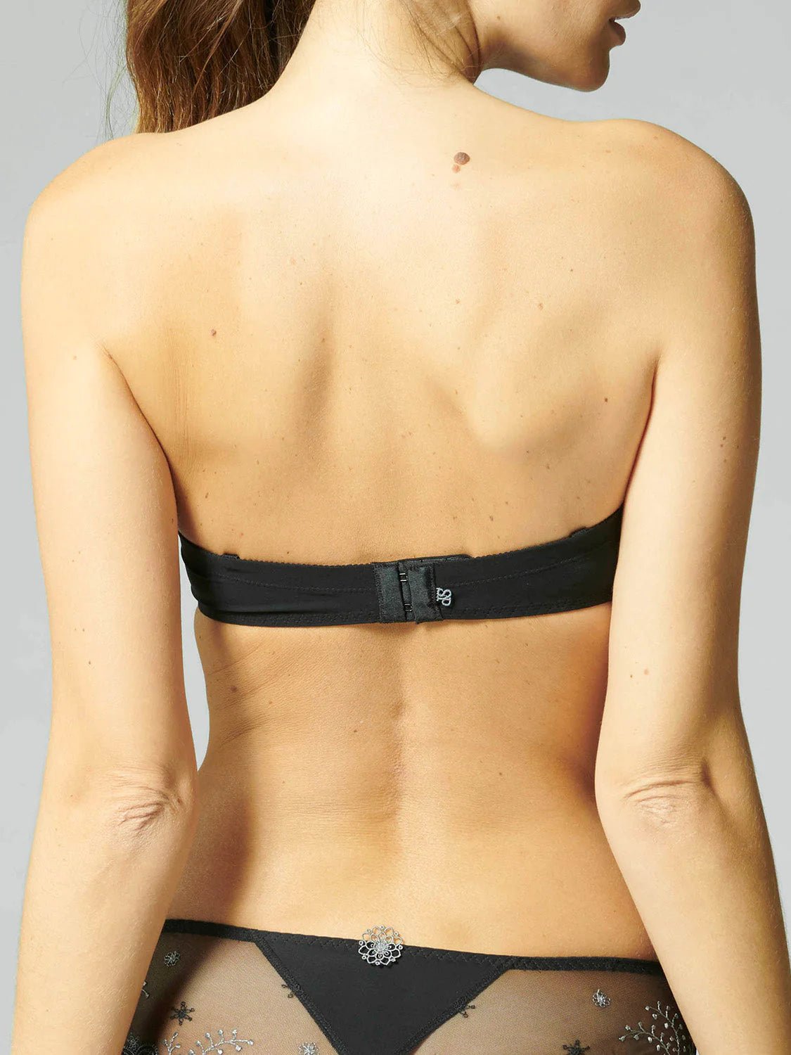 Model wearing Simone Pérèle Delice Strapless Bra in Moonlight from The Foundation, featuring smooth microfibre cups and embroidered tulle detailing. back view