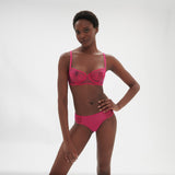 Model standing in Intrigue Half Cup Bra Disco Pink by Simone Perele, emphasising contemporary, fashion-forward style from The Foundation.