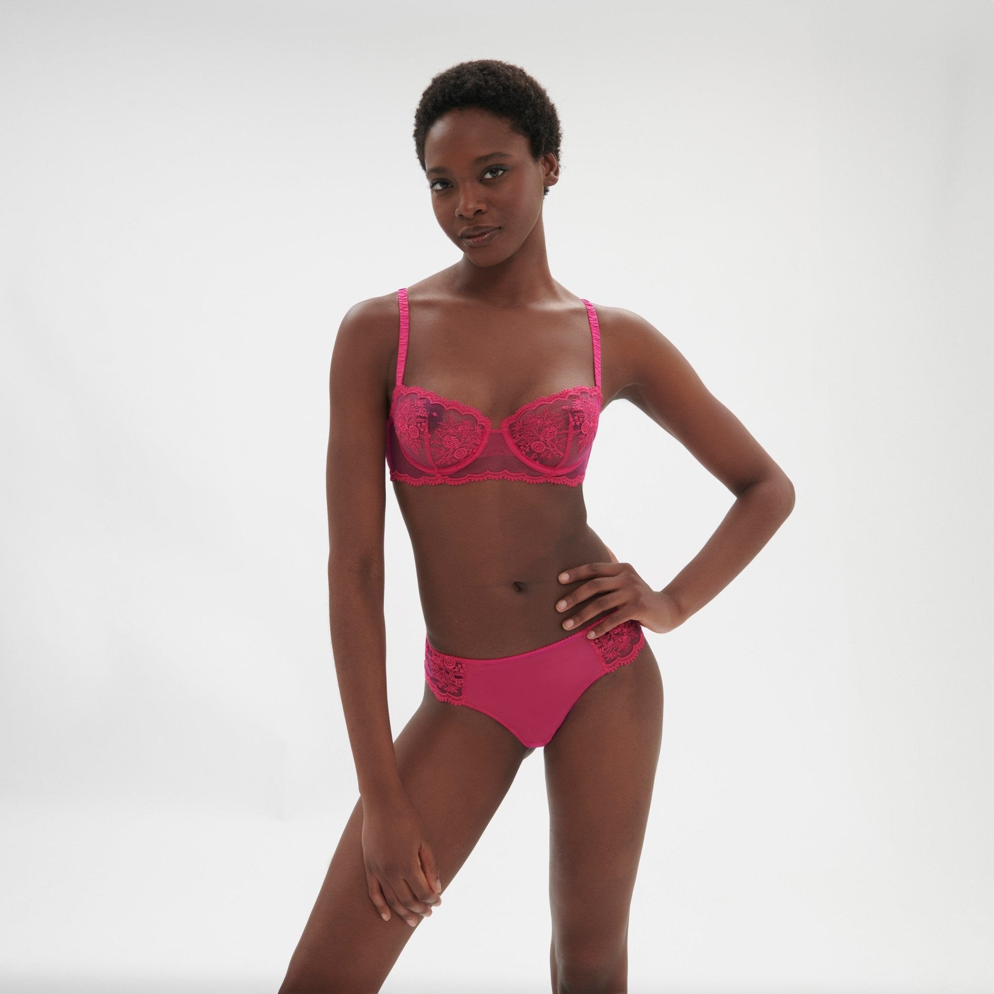 Model standing in Intrigue Half Cup Bra Disco Pink by Simone Perele, emphasising contemporary, fashion-forward style from The Foundation.