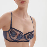 Close-up of Simone Perele Intrigue Half Cup Bra in Cinder Blue, revealing intricate blue floral embroidery and tulle detail, exclusive to The Foundation.