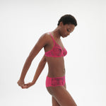 Model turned to the side in Intrigue Shorty Brief Disco Pink by Simone Perele, highlighting embroidery and fit from The Foundation.