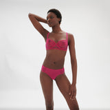 Model in Intrigue Tanga Disco Pink with matching bra, showing detailed embroidery and couture look from The Foundation.