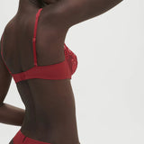 Model wearing Saga Half Cup Bra Lipstick from The Foundation, angled front to show deep plunging neckline and elegant lace