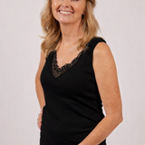 Woman wearing a black sleeveless top with lace details on a plain background