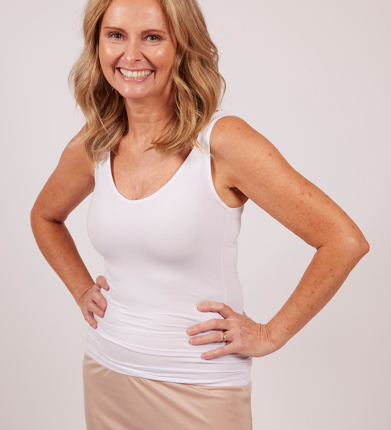 Woman in a white modal tank top by EGI, showing front fit and scoop neckline.