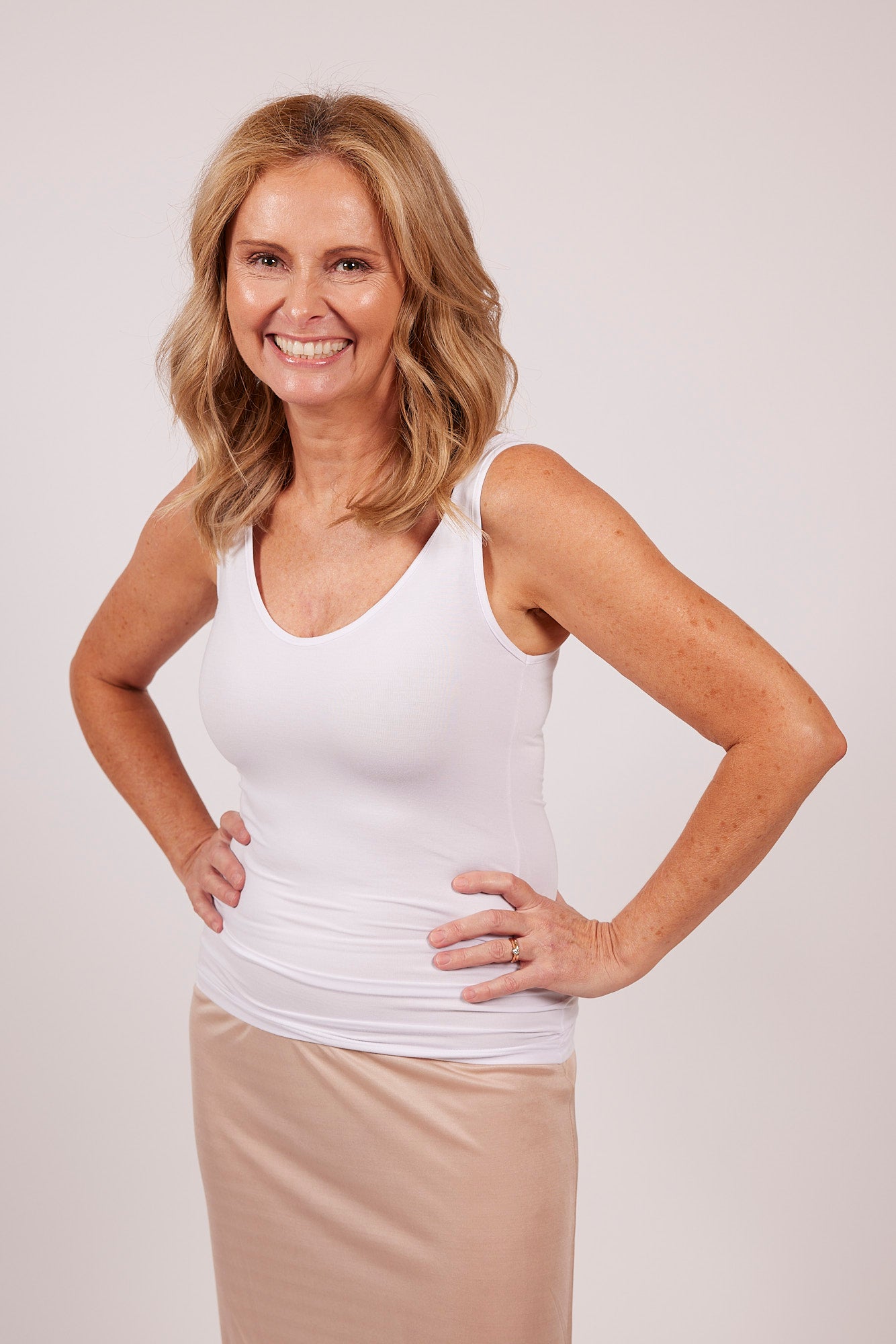 Woman in a white modal tank top by EGI, showing front fit and scoop neckline.