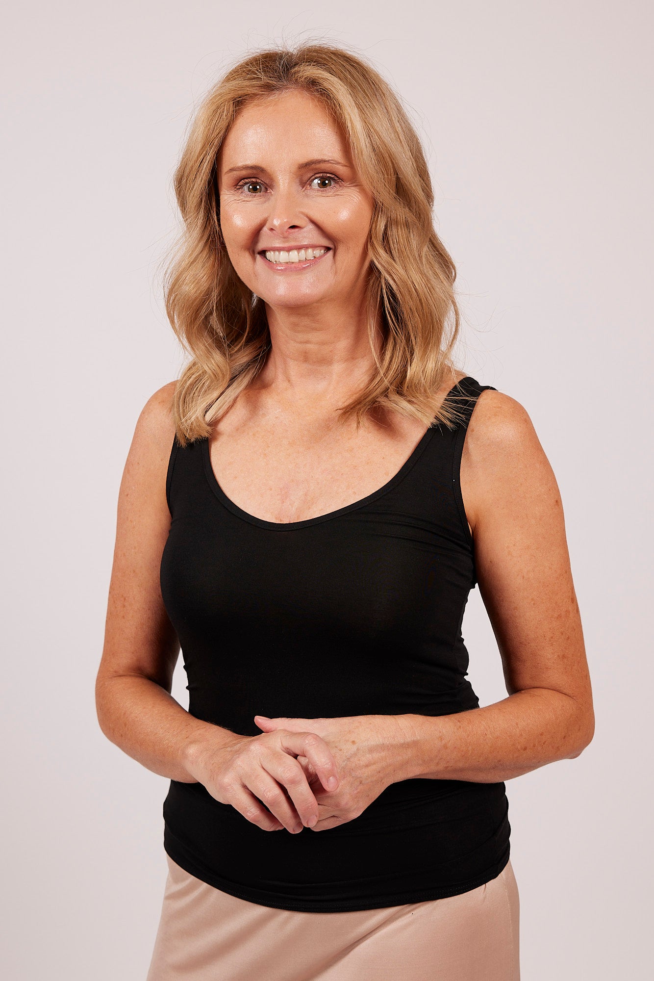 Woman in black EGI modal tank top, showcasing front fit with scoop neckline.