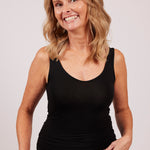 Front-side angle of woman wearing black modal tank top, showing fit around bust and waist.
