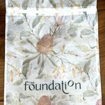 Flat lay of The Foundation Wash Bag with visible Foundation logo and floral print design.