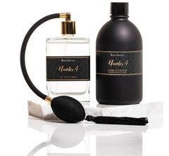 Noir Laundry Gift Set with black scented wash bottle, atomiser, and fragrance spray, displayed with satin ribbon and packaging.
