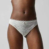 Front view of the Waltz Tanga Brief Milk Ivory from The Foundation – mid-rise lace thong with delicate scalloped trim and sheer floral panelling.
