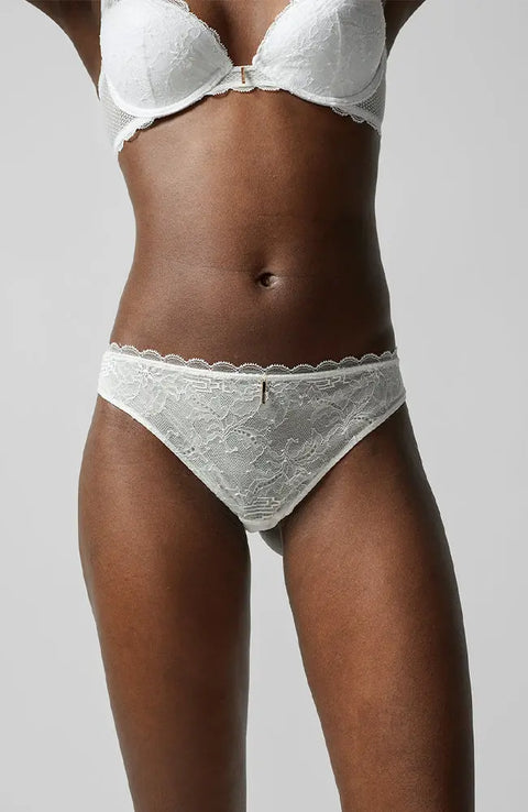Front view of the Waltz Tanga Brief Milk Ivory from The Foundation – mid-rise lace thong with delicate scalloped trim and sheer floral panelling.