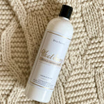 500ml Bon Savvy Wool & Cashmere Savvy Laundry Liquid bottle laying on soft knitwear, showcasing premium eco-conscious packaging.