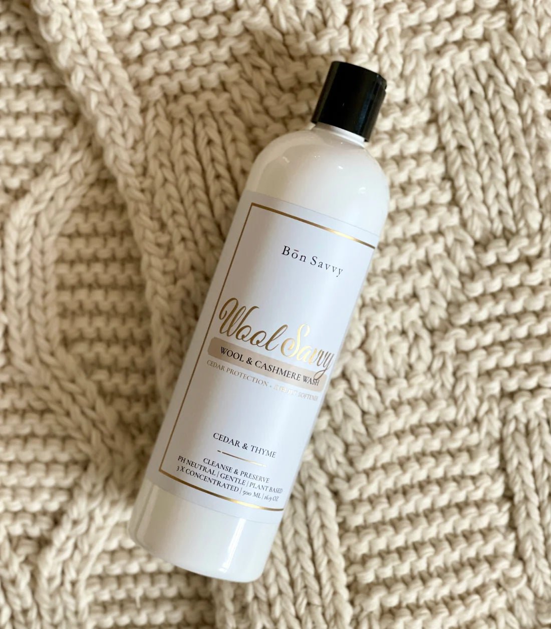 500ml Bon Savvy Wool & Cashmere Savvy Laundry Liquid bottle laying on soft knitwear, showcasing premium eco-conscious packaging.
