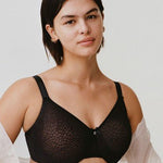 Model wearing Chantelle’s C Magnifique Moulded Bra in Black from The Foundation, featuring full-coverage cups and a smoothing mesh back band.
