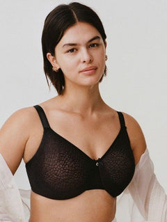 Model wearing Chantelle’s C Magnifique Moulded Bra in Black from The Foundation, featuring full-coverage cups and a smoothing mesh back band.