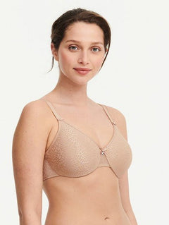 Model in Chantelle C Magnifique Moulded Bra in Nude from The Foundation, featuring seamless full cups, minimising support, and soft mesh band.