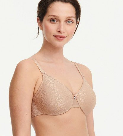 Model in Chantelle C Magnifique Moulded Bra in Nude from The Foundation, featuring seamless full cups, minimising support, and soft mesh band.