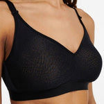 Close-up angled view of the wireless black C Magnifique bra, highlighting matte-shine floral texture and banded base.