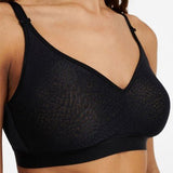 Close-up angled view of the wireless black C Magnifique bra, highlighting matte-shine floral texture and banded base.
