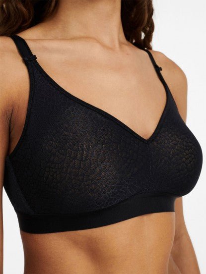 Close-up angled view of the wireless black C Magnifique bra, highlighting matte-shine floral texture and banded base.
