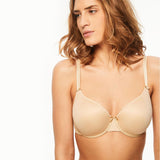 The Foundation’s Basic Invisible Memory Bra in Skin shown front-on, featuring smooth memory foam cups and a seamless fit.