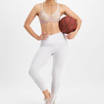 Woman in athletic pose wearing Electrify Mesh Underwire Sports Bra Soft Powder, showcasing active fit from The Foundation.