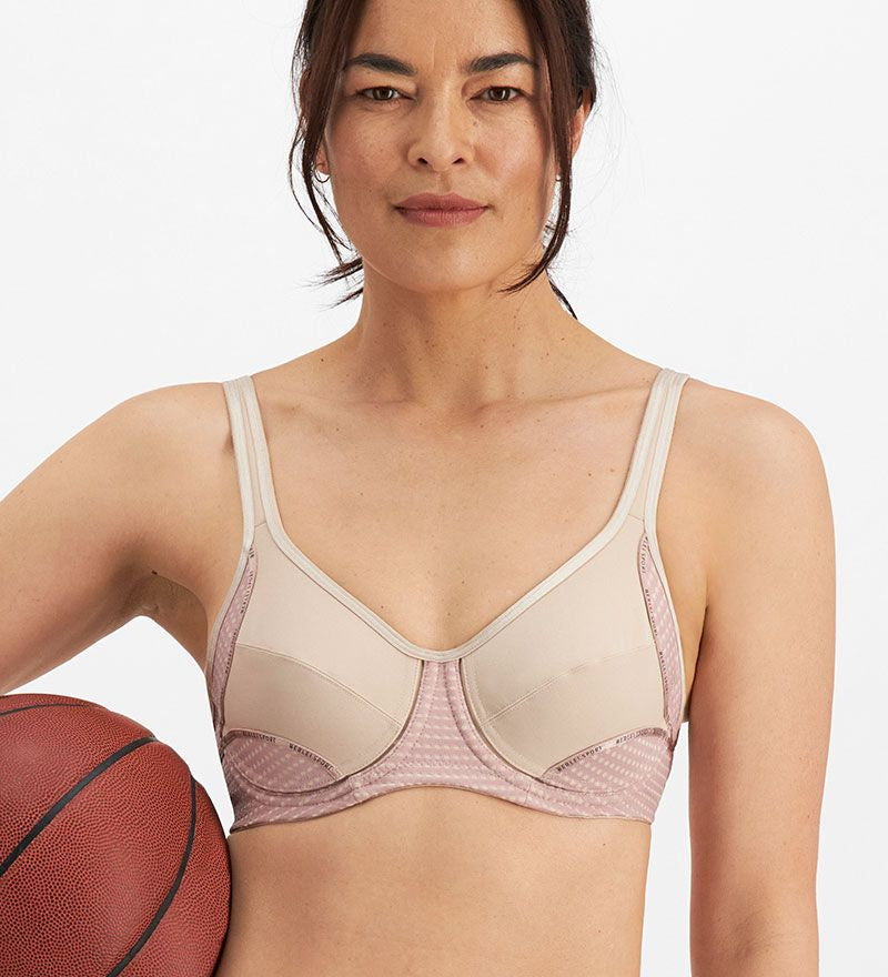 Woman wearing the Electrify Mesh Underwire Sports Bra in Soft Powder, front view with sports styling, available at The Foundation.