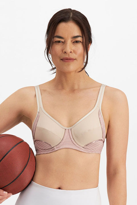 Woman wearing the Electrify Mesh Underwire Sports Bra in Soft Powder, front view with sports styling, available at The Foundation.